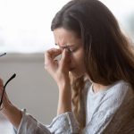 A womman suffering from a tension headache rubbing her eyes