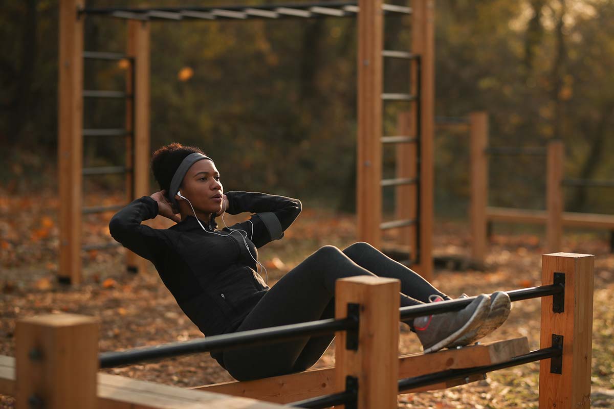 Woman doing sit-ups in an outdoor workout setting, emphasizing recovery and massage for athletes.